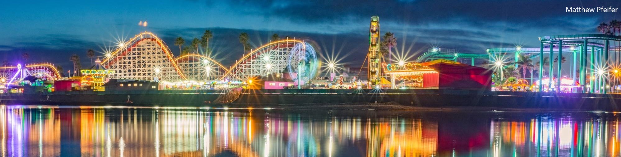 Crop from Matthew Pfeifer's photo of the Santa Cruz Boardwalk at night, lights reflecting on the water