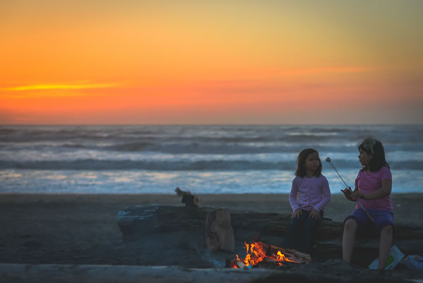Two girls sitting by a campfire roasting marshmallows, Samoa Beach, by Carissa Ranario
