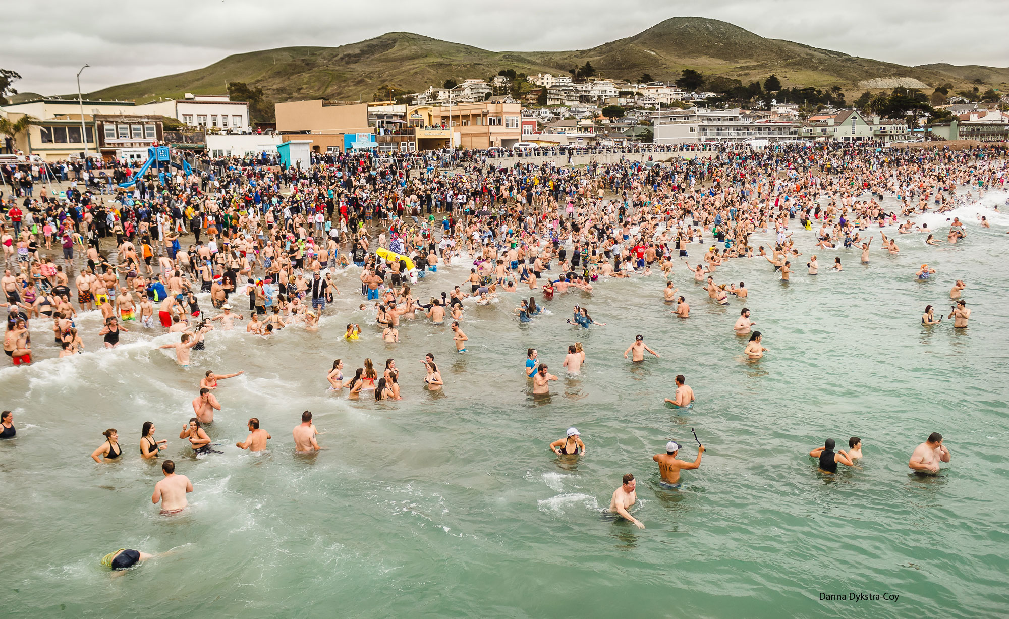 Cayucos Beach full of swimmers for the annual Polar Bear Plunge, taken from the Pier