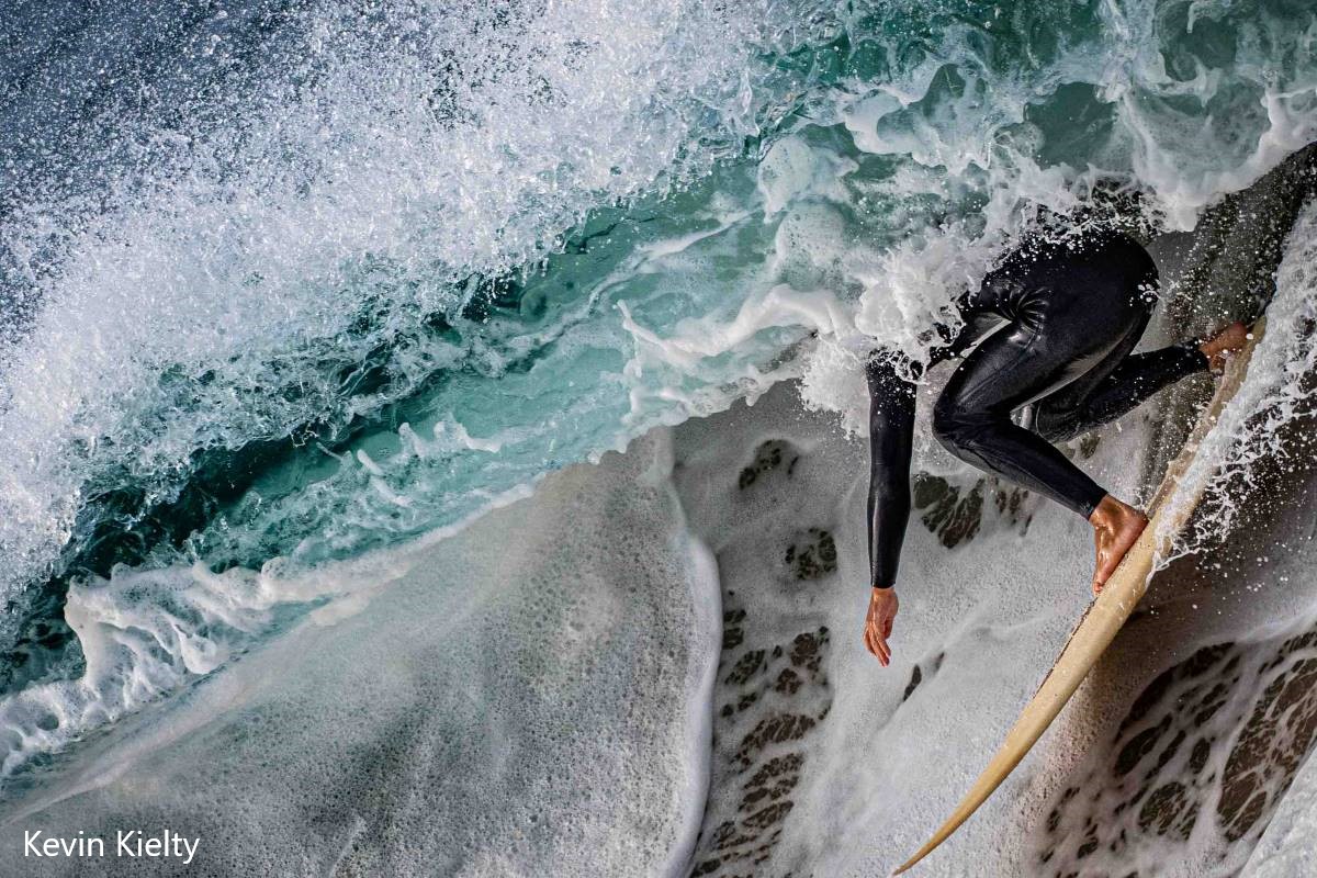 A negative 45 degree crop of a foamy barrel, the bottom half of a surfer in view