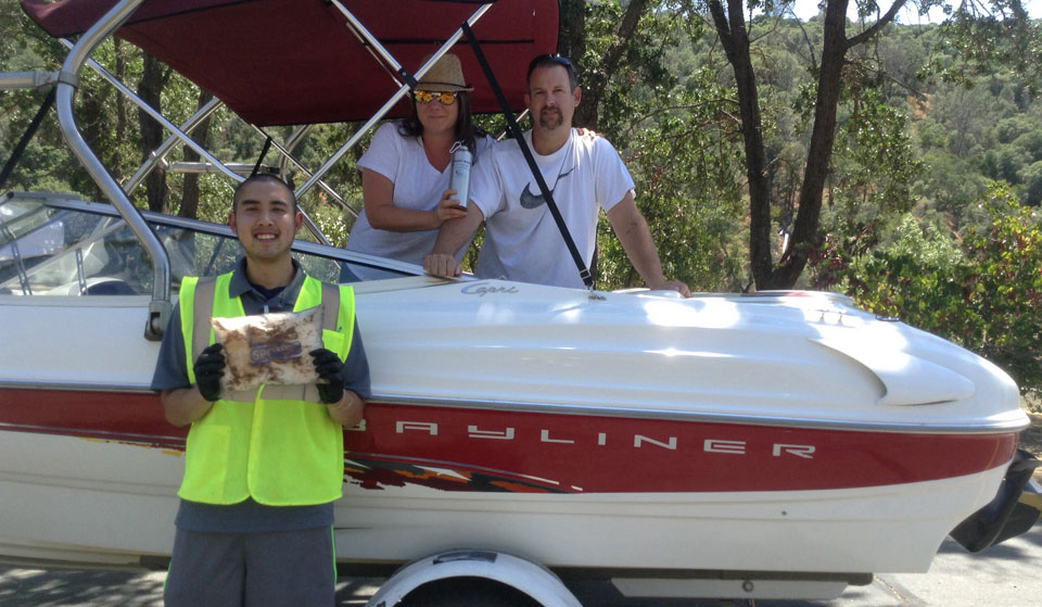 A Dockwalker volunteer demonstrates the use of an oil absorbant pad for two boaters