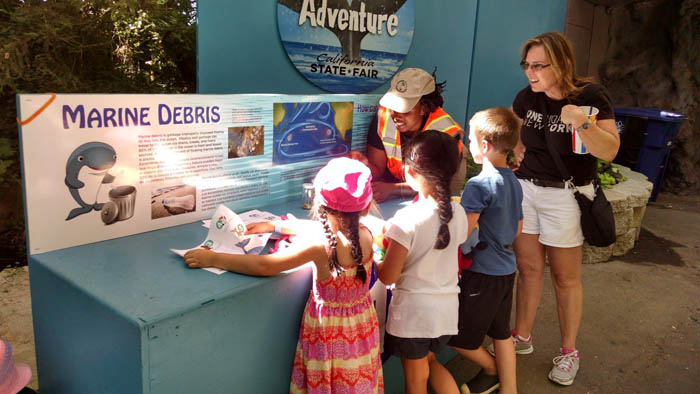 A Family gathers around an ocean awareness table at the California State Fair