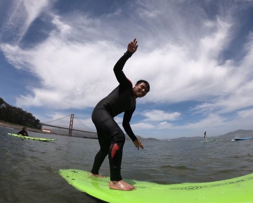 young man surfs in front of the Golden Gate Bridge