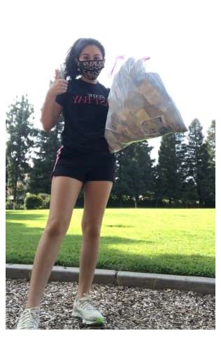 a woman holding a full trash bag gives a thumbs up