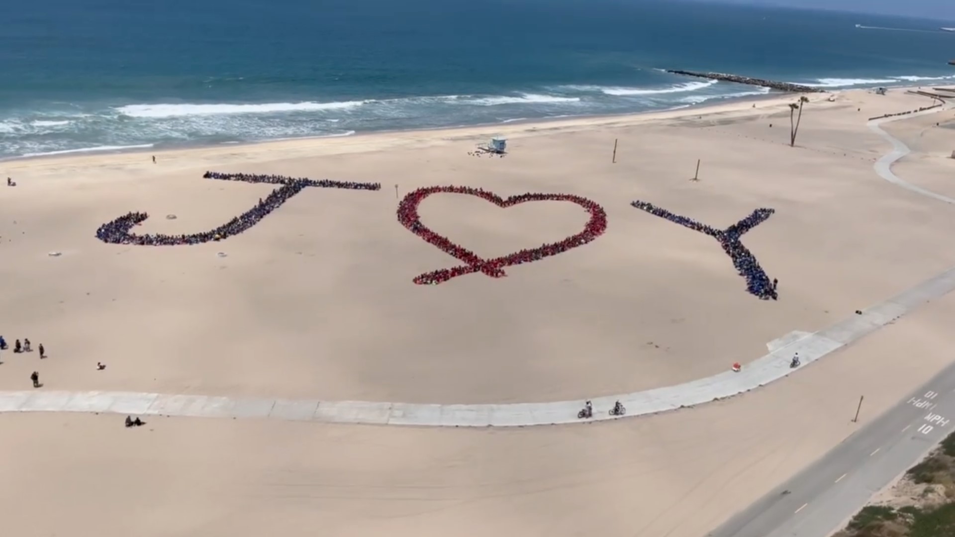 Los Angeles County Kids' Ocean Day aerial artwork. People on the sand form the word JOY.